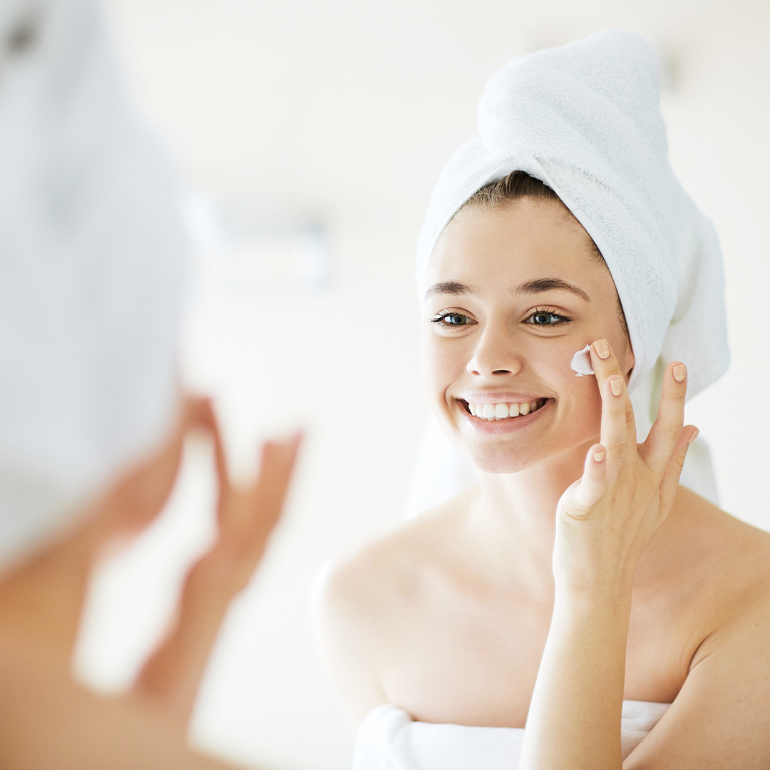 Woman putting face cream after a bath