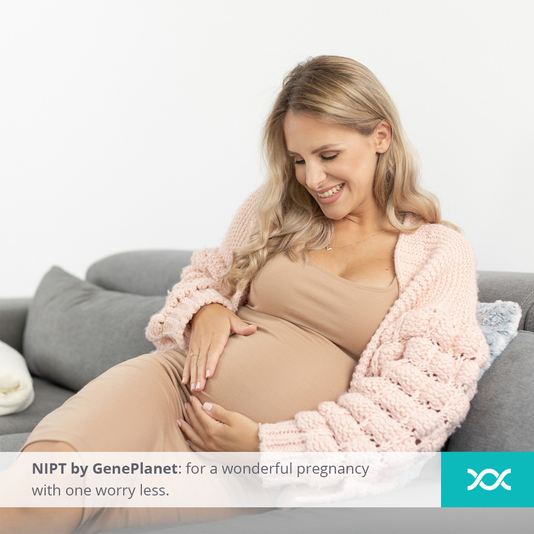 Pregnant lady sitting on a sofa, touching her stomach and smiling